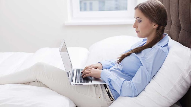woman on couch typing on laptop